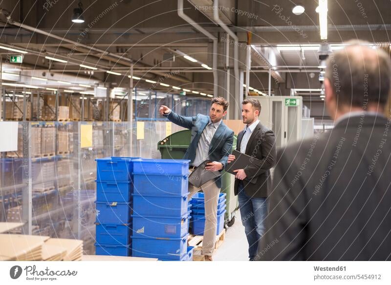Three businessmen in factory warehouse working At Work storehouse storage colleagues Businessman Business man Businessmen Business men talking speaking males