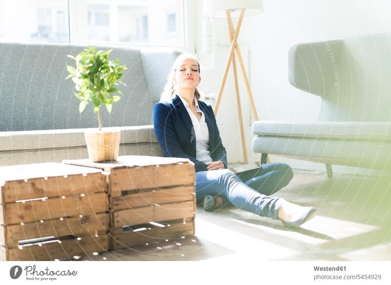 Businesswoman sitting on the floor relaxing females women relaxed relaxation Seated businesswoman businesswomen business woman business women Adults grown-ups