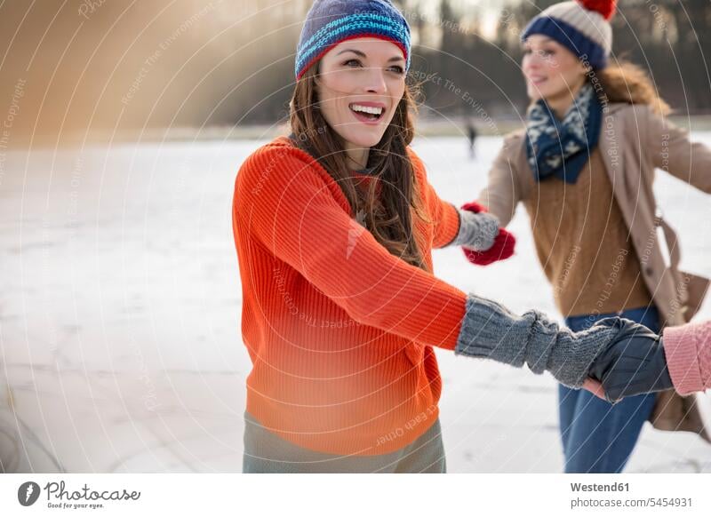 Female friends ice skating in a circle on frozen lake ice skater skaters ice skaters happiness happy laughing Laughter Ice-Skating winter sport Winter Sports