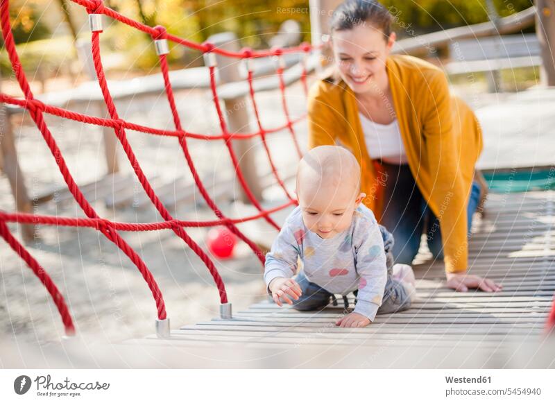 Mother watching her baby girl playing on playground infants nurselings babies play yard play ground playgrounds baby girls female alertness mother mommy mothers