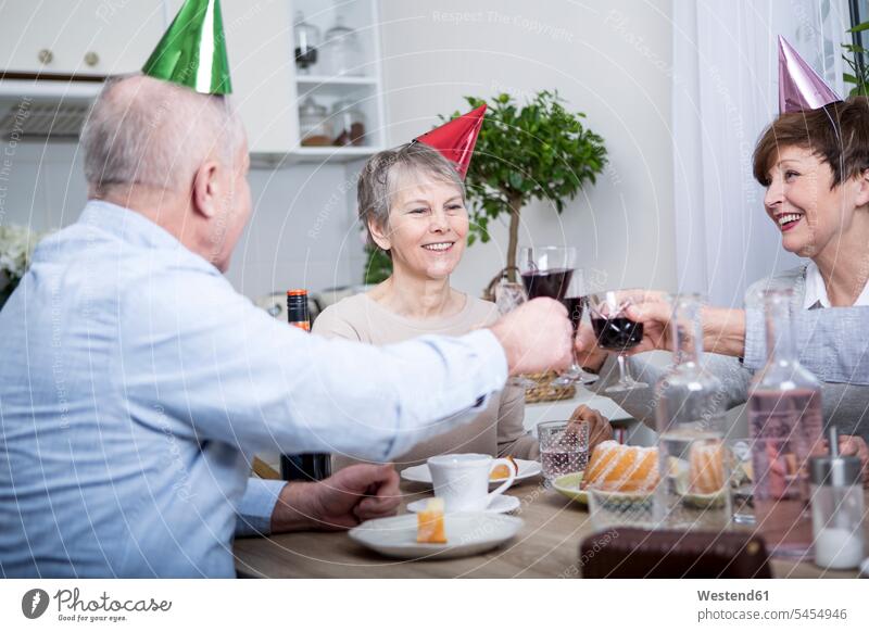 Two senior couples celebrating birthday party, toasting with red wine clinking cheers Red Wine Red Wines drinking celebrate partying Birthday