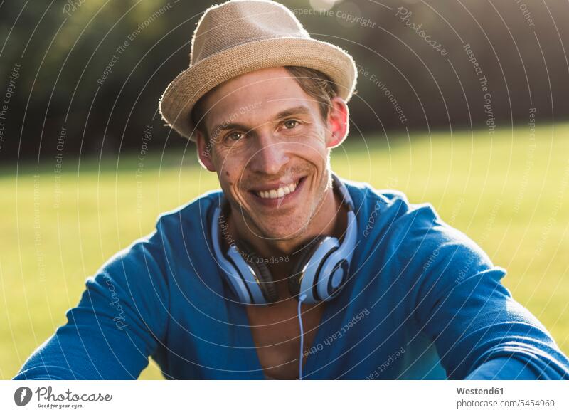 Portrait of laughing man with hat and headphones in a park portrait portraits hats men males Adults grown-ups grownups adult people persons human being humans