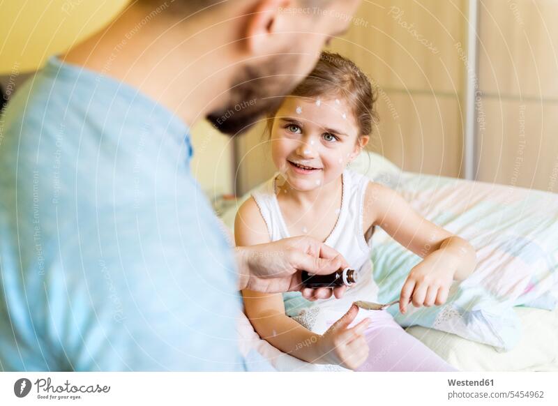 Girl having chickenpox receiving medicine in bed daughter daughters ill sick smiling smile father pa fathers daddy dads papa drops child children family