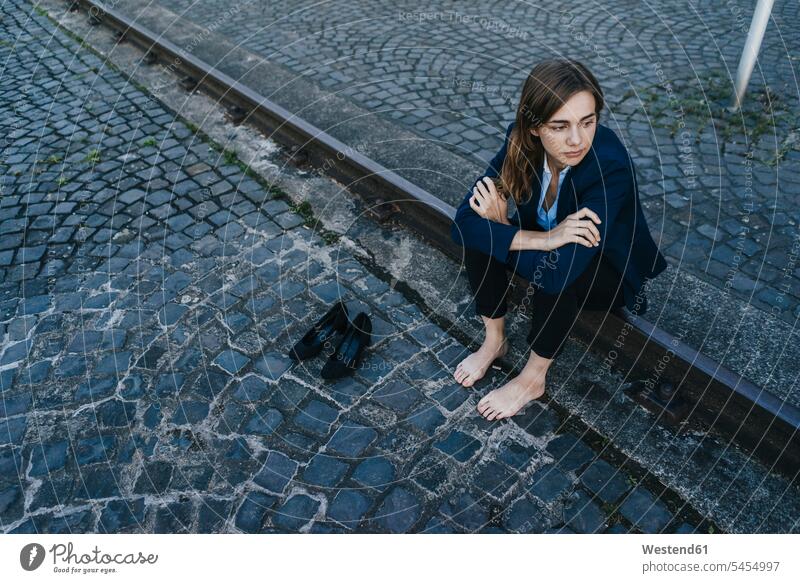 Barefoot businesswoman sitting on rail serious earnest Seriousness austere thinking smart smart casual smart-casual Business Casual well dressed