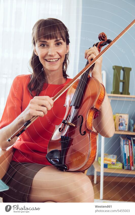 Portrait of a woman with violin in children’s room playing smiling smile violins practicing practice practise exercise exercising practising females women