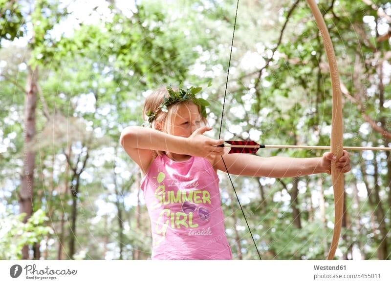 Girl shooting with bow and arrow in the forest arrows girl females girls woods forests archery child children kid kids people persons human being humans