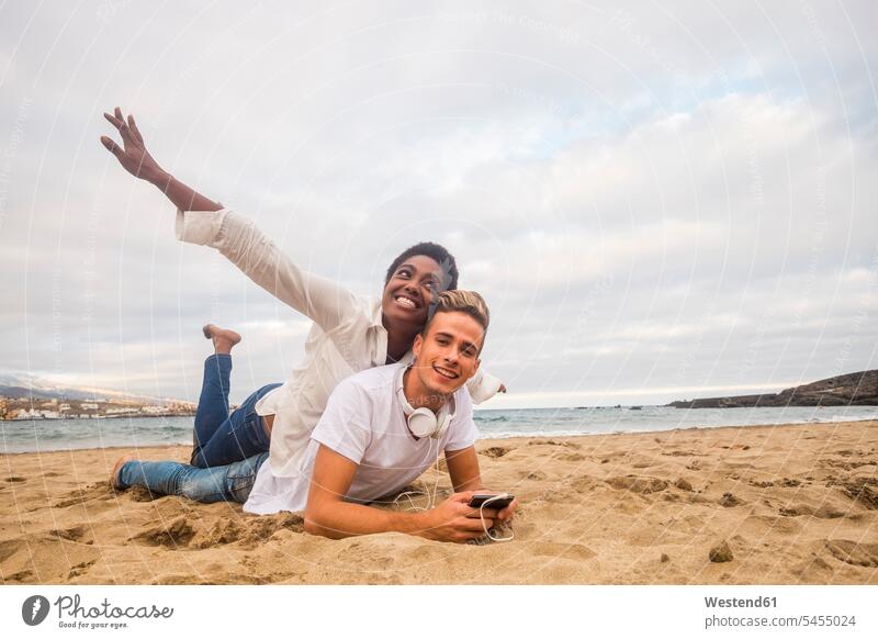 Happy young couple on the beach twosomes partnership couples beaches people persons human being humans human beings Sea ocean lying laying down lie lying down