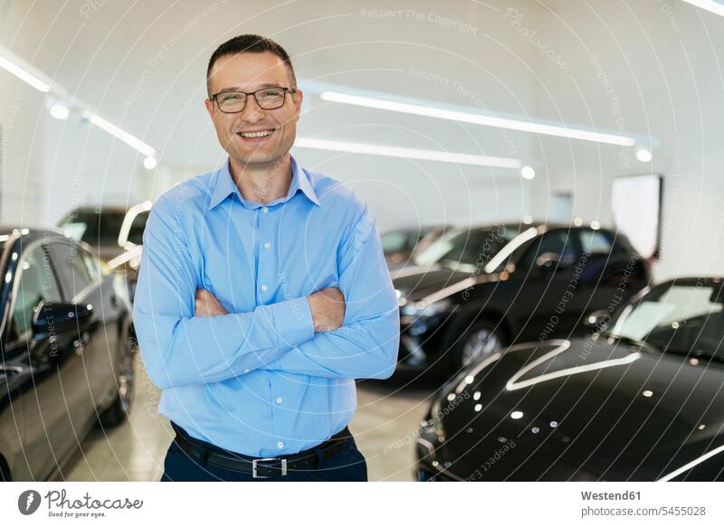 Car dealer standing in his shop copy space seller sellers selling smiling smile car automobile Auto cars motorcars Automobiles car dealer car dealers