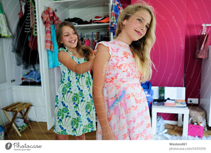 Two girls putting on dresses females trying on fit fitting dressing female friends clothing clothes smiling smile child children kid kids people persons