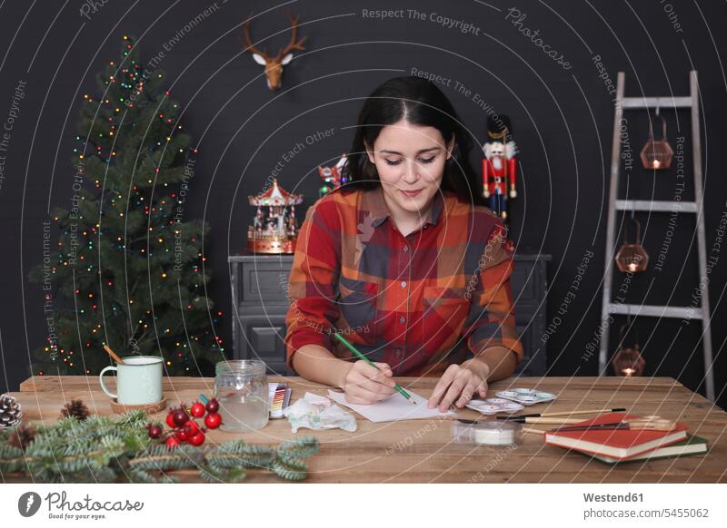 Young woman drawing Christmas card with pencil sketching females women Christmas cards Adults grown-ups grownups adult people persons human being humans