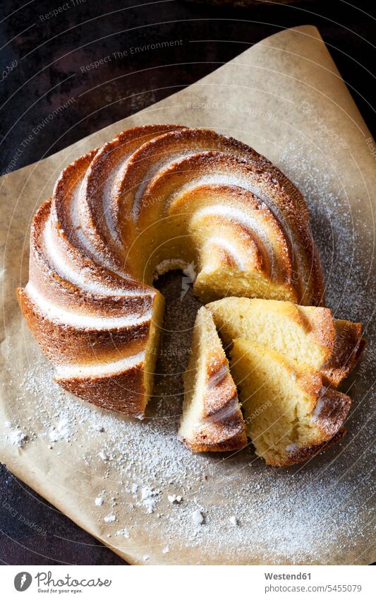 Sliced Gugelhupf sprinkled with icing sugar on parchment paper nobody copy space prepared baked Baked Food Ring Cake Bundt Cake Ring Cakes Bundt Cakes sweet