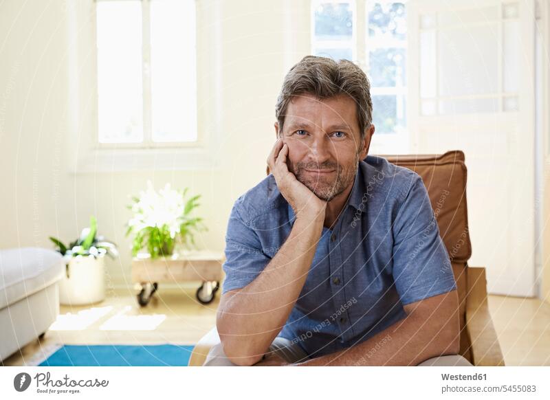 Man sitting with head in head, smiling armchair Arm Chairs armchairs home at home happiness happy comfortable amenities amenity Seated smile man males Adults
