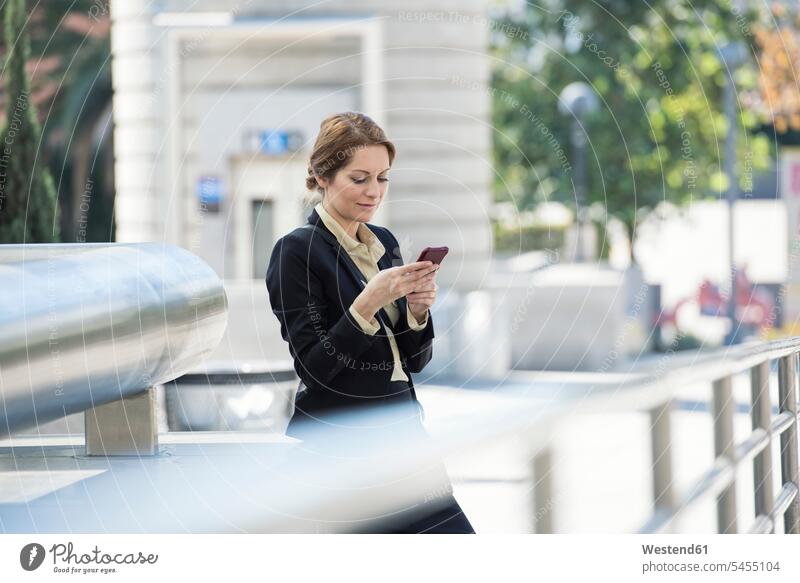 Businesswoman checking cell phone outdoors mobile phone mobiles mobile phones Cellphone cell phones businesswoman businesswomen business woman business women