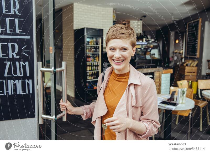 Female cafe owner unlocking the door in the morning smiling smile woman females women Adults grown-ups grownups adult people persons human being humans