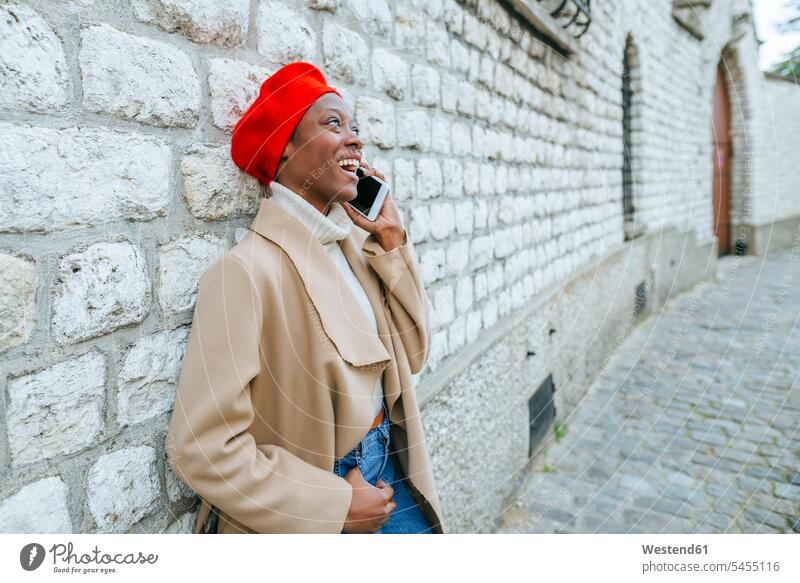 Young woman in Paris leaning against wall and talking on the phone females women Smartphone iPhone Smartphones call telephoning On The Telephone calling smiling