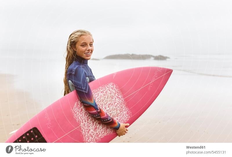 Spain, Aviles, young surfer holding surfboard on the beach smiling smile surfboards female surfer surfers female surfers sea ocean beaches Teenage Girls
