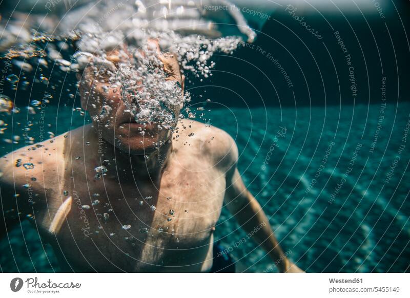 Man making air bubbles underwater in a swimming pool submerged Under Water underwater shot underwater shots pools swimming pools man men males Adults grown-ups