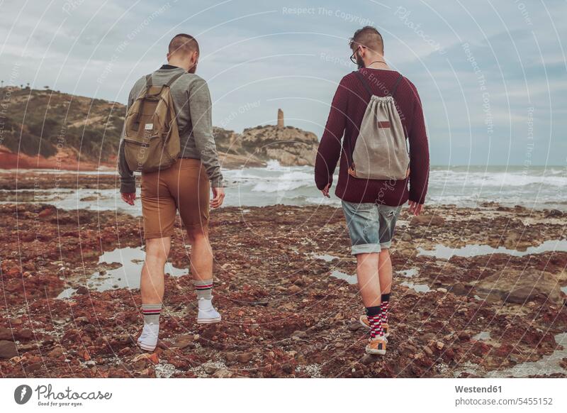 Spain, Oropesa del Mar, two young men walking on stony beach beaches couple twosomes partnership couples people persons human being humans human beings