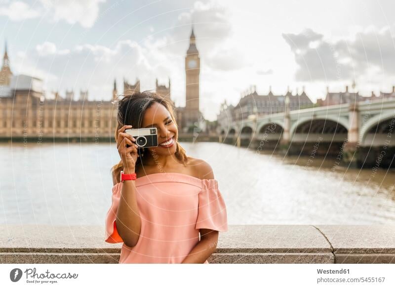 UK, London, beautiful woman taking a picture near Westminster Bridge smiling smile females women photographing camera cameras Adults grown-ups grownups adult