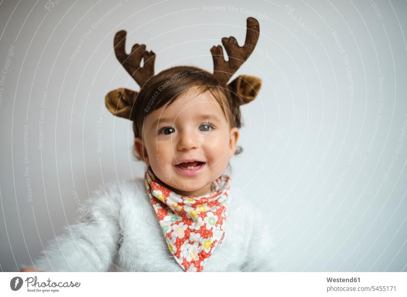 Portrait of laughing baby girl with reindeer antlers headband Antler Antlers Laughter baby girls female portrait portraits caribu caribou reindeers animal head