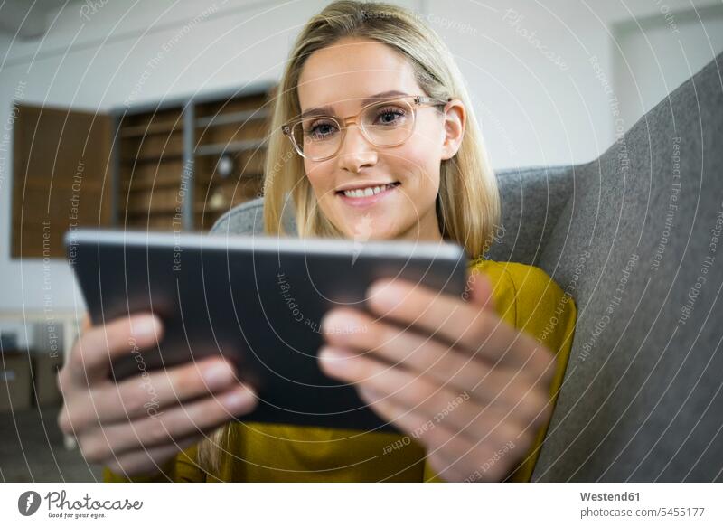 Portrait of smiling woman with glasses sitting on couch using mini tablet digitizer Tablet Computer Tablet PC Tablet Computers iPad Digital Tablet