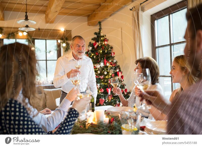 Senior man holding a speech with family at Christmas dinner X-Mas yule Xmas X mas families celebrating celebrate partying celebration Red-Letter Day Festive Day