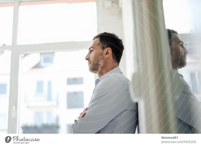 Businessman in office leaning against wall at the window Business man Businessmen Business men windows business people businesspeople business world