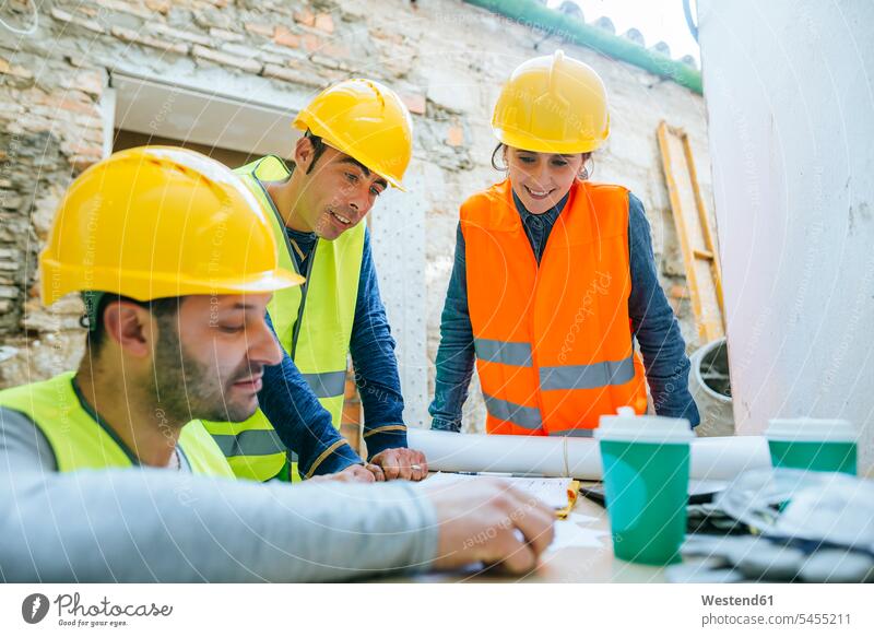 Smiling woman and two construction workers on construction site builders Building Site sites Building Sites construction sites colleagues smiling smile