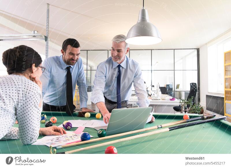 Business people standing at pool table with laptop, discussing investment strategy billiard table billiard tables Laptop Computers laptops notebook strategic