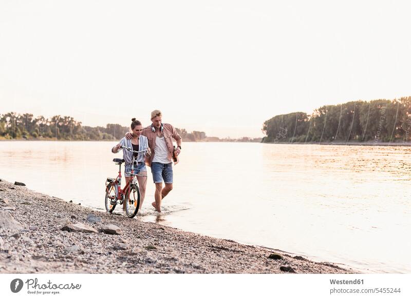 Young couple with bicycle wading in river walking going twosomes partnership couples people persons human being humans human beings River Rivers water waters
