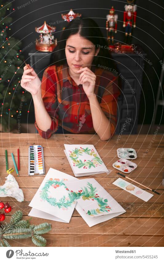 Young woman painting Christmas card with water colors females women portrait portraits Christmas cards Adults grown-ups grownups adult people persons