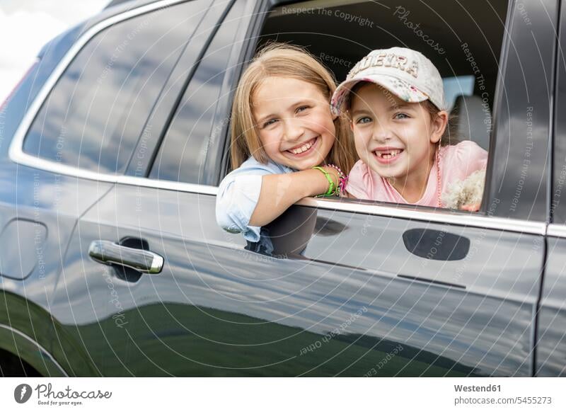 Girls sitting in car, looking out of window sister sisters girl females girls vacation Holidays happiness happy automobile Auto cars motorcars Automobiles