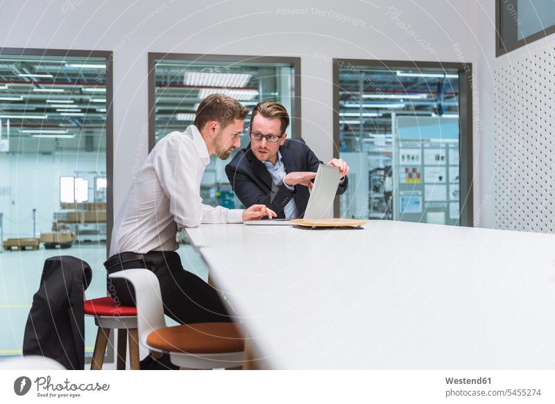 Two businessmen sitting in modern office, discussing in front of laptop colleagues team Businessman Business man Businessmen Business men work meeting briefing
