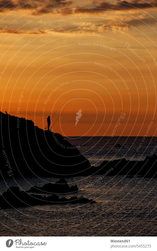 Spain, Costa Brava, Blanes, lone angler and Sa Palomera rock silhouette at sunrise by the Mediterranean Sea rocks View Vista Look-Out outlook morning light man