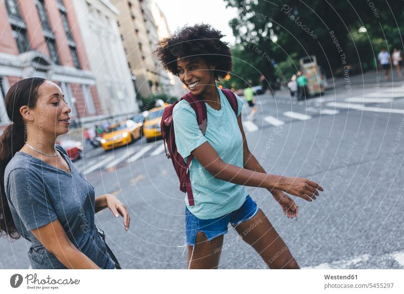 USA, New York City, two friends crossing the street road streets roads female friends mate friendship woman females women smiling smile walking going Adults