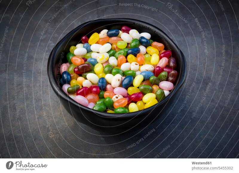 Bowl of colourful sweet jellybeans on grey background Bowls large group of objects many objects Sugary sweets gleaming abundance Plentiful Unhealthy Eating