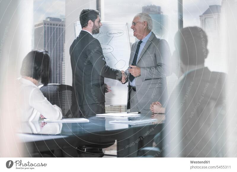 Two businessmen shaking hands at office meeting presentation presentations Businessman Business man Businessmen Business men Business Meeting