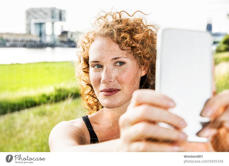 Germany, Cologne, portrait of freckled young woman taking selfie with cell phone portraits females women Selfie Selfies freckles Adults grown-ups grownups adult