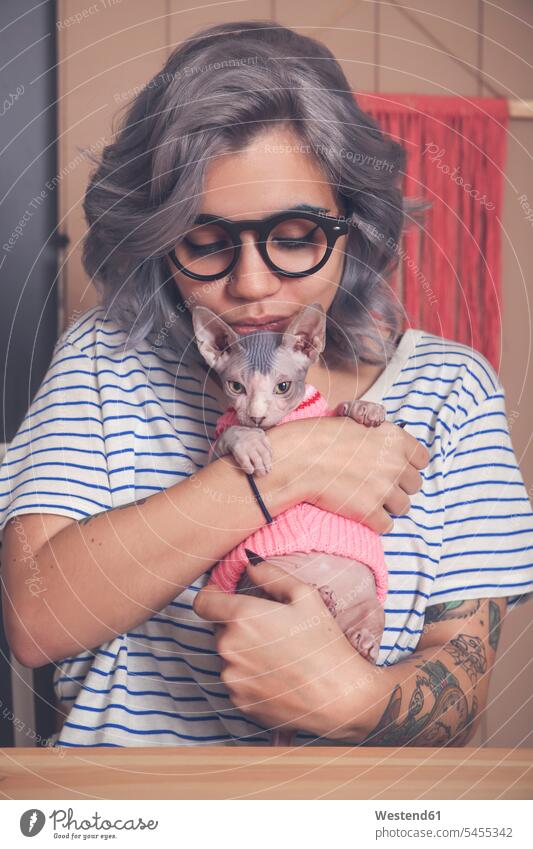 Young woman holding Sphynx cat wearing pullover sweater jumper Sweaters cats females women pets animal creatures animals Adults grown-ups grownups adult people