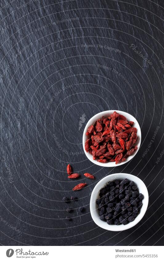 Bowls of goji and chokeberries on slate food and drink Nutrition Alimentation Food and Drinks Goji Chinese boxthorn Chinese wolfberries Lycium barbarum