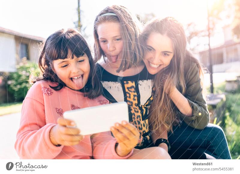 Three playful girls taking a selfie outdoors sister sisters portrait portraits Selfie Selfies Fun having fun funny mobile phone mobiles mobile phones Cellphone