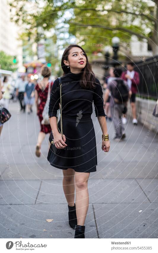 USA, New York City, Manhattan, fashionable young woman dressed in black walking on pavement females women Adults grown-ups grownups adult people persons