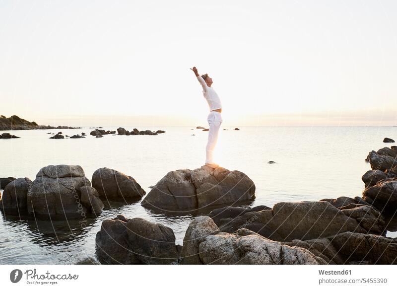 Mature man doing yoga exercise on a rock at the sea men males Sea ocean Adults grown-ups grownups adult people persons human being humans human beings