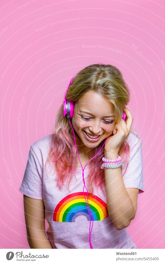 Portrait of young woman listening to music with headphones in front of pink background females women headset portrait portraits Adults grown-ups grownups adult