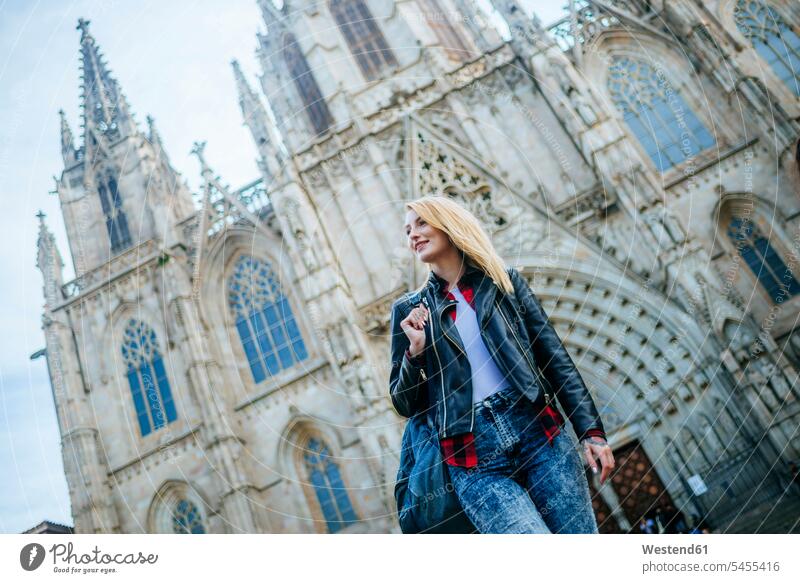 Spain, Barcelona, smiling young woman walking in front of cathedral females women Adults grown-ups grownups adult people persons human being humans human beings