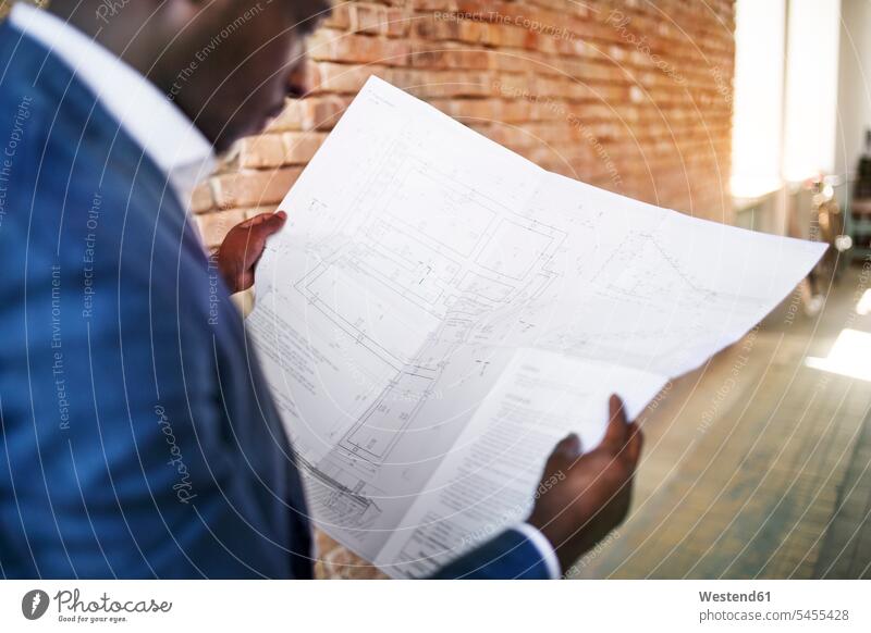 Businessman studying construction plan at brick wall Business man Businessmen Business men architect architects plans business people businesspeople