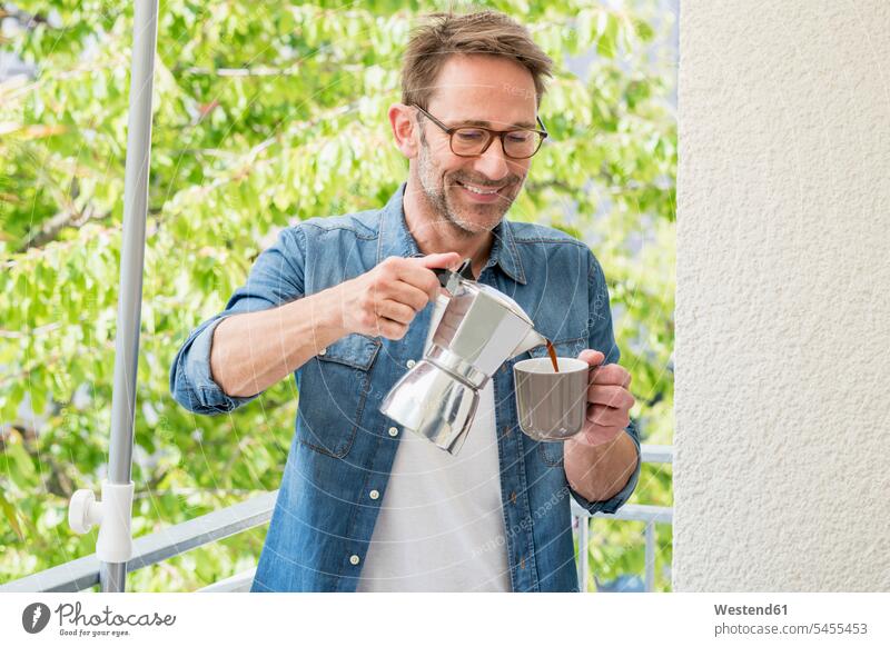 Smiling mature man on balcony pouring coffee in a cup balconies men males Adults grown-ups grownups adult people persons human being humans human beings