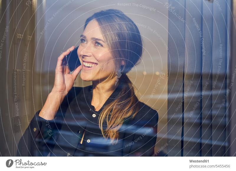 Portrait of laughing businesswoman on the phone behind windowpane call telephoning On The Telephone calling windows portrait portraits businesswomen