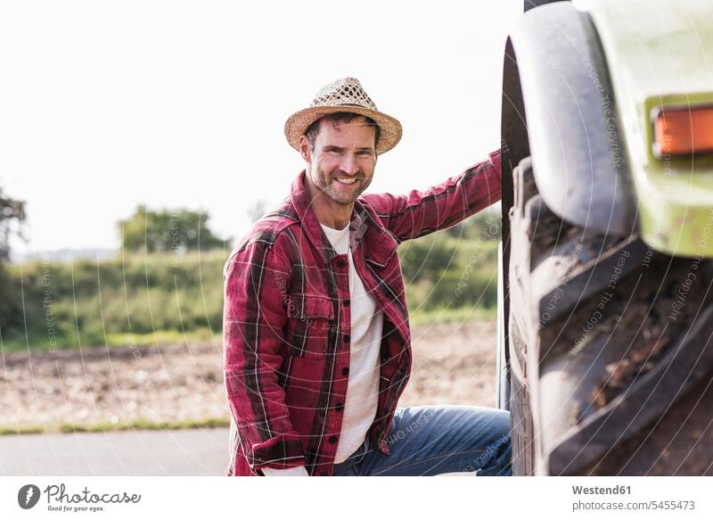 Portrait of confident farmer with tractor portrait portraits man men males agriculturists farmers smiling smile motor vehicle road vehicle road vehicles