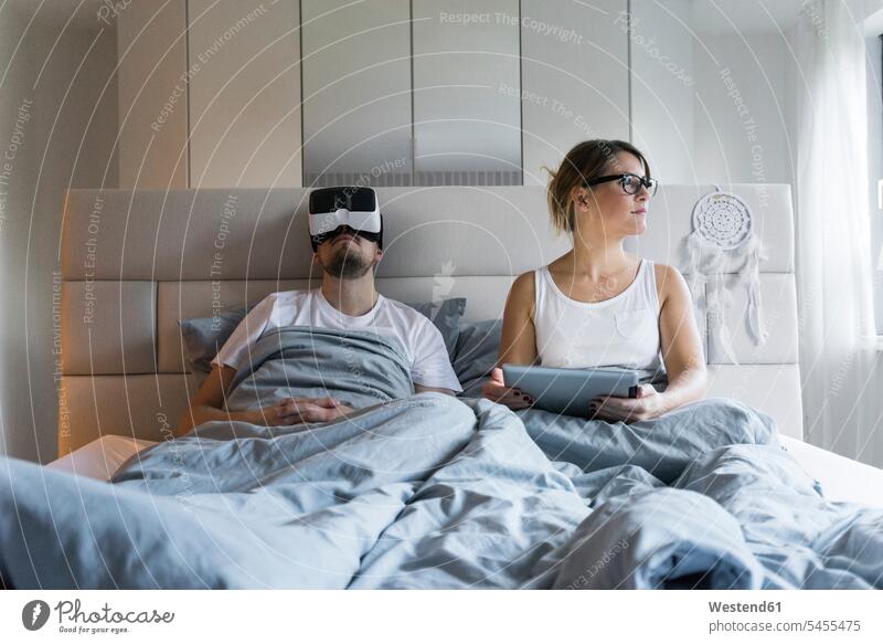 Couple in bed at home with tablet and VR glasses specs Eye Glasses spectacles Eyeglasses virtual reality digitizer Tablet Computer Tablet PC Tablet Computers